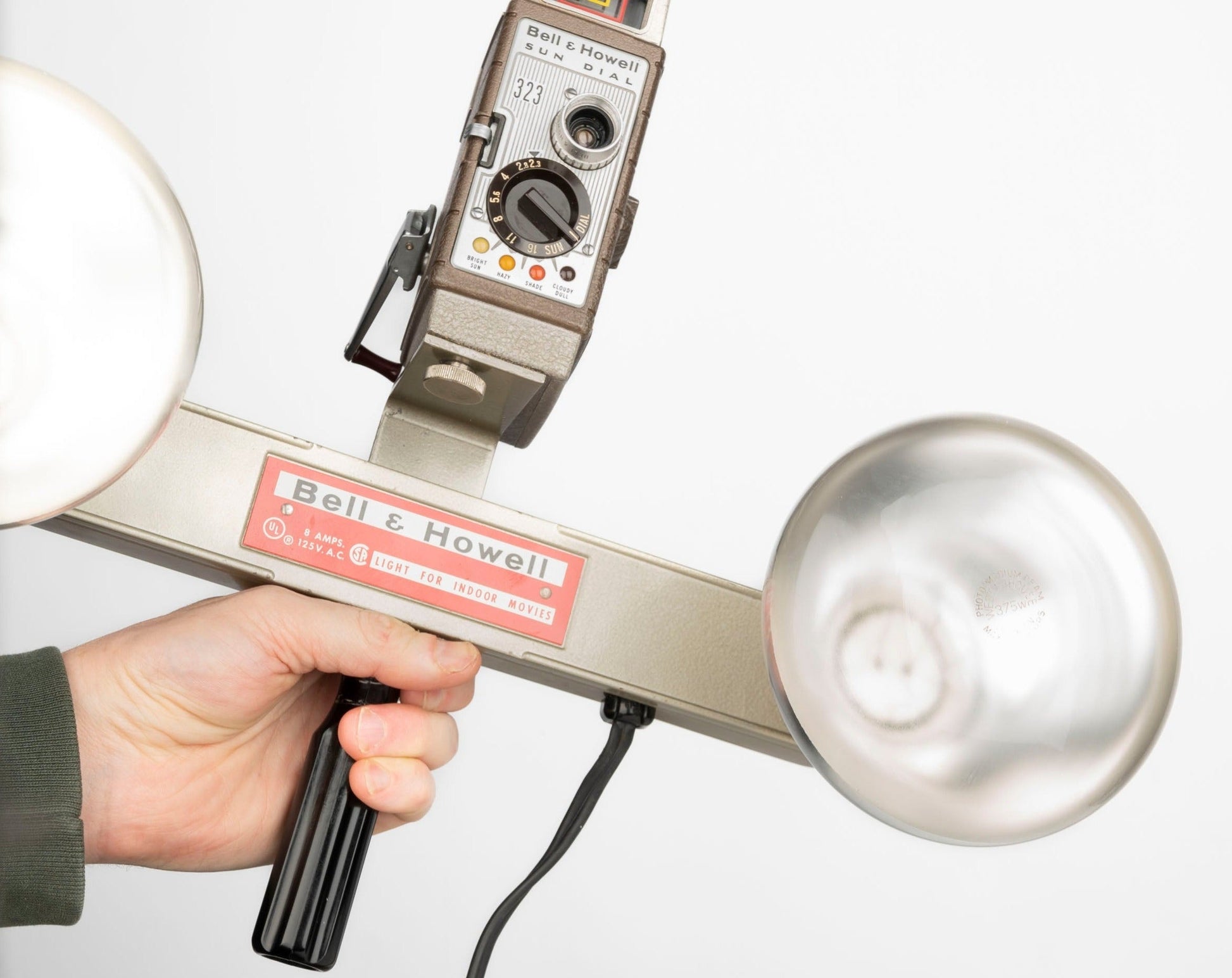 Bell and Howell 323 Sun Dial 8mm camera shown attached to indoor movie light bar