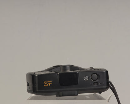 The Canon Snappy QT is a 35mm film point-and-shoot camera featuring a 32mm lens and an unusually large and bright viewfinder.