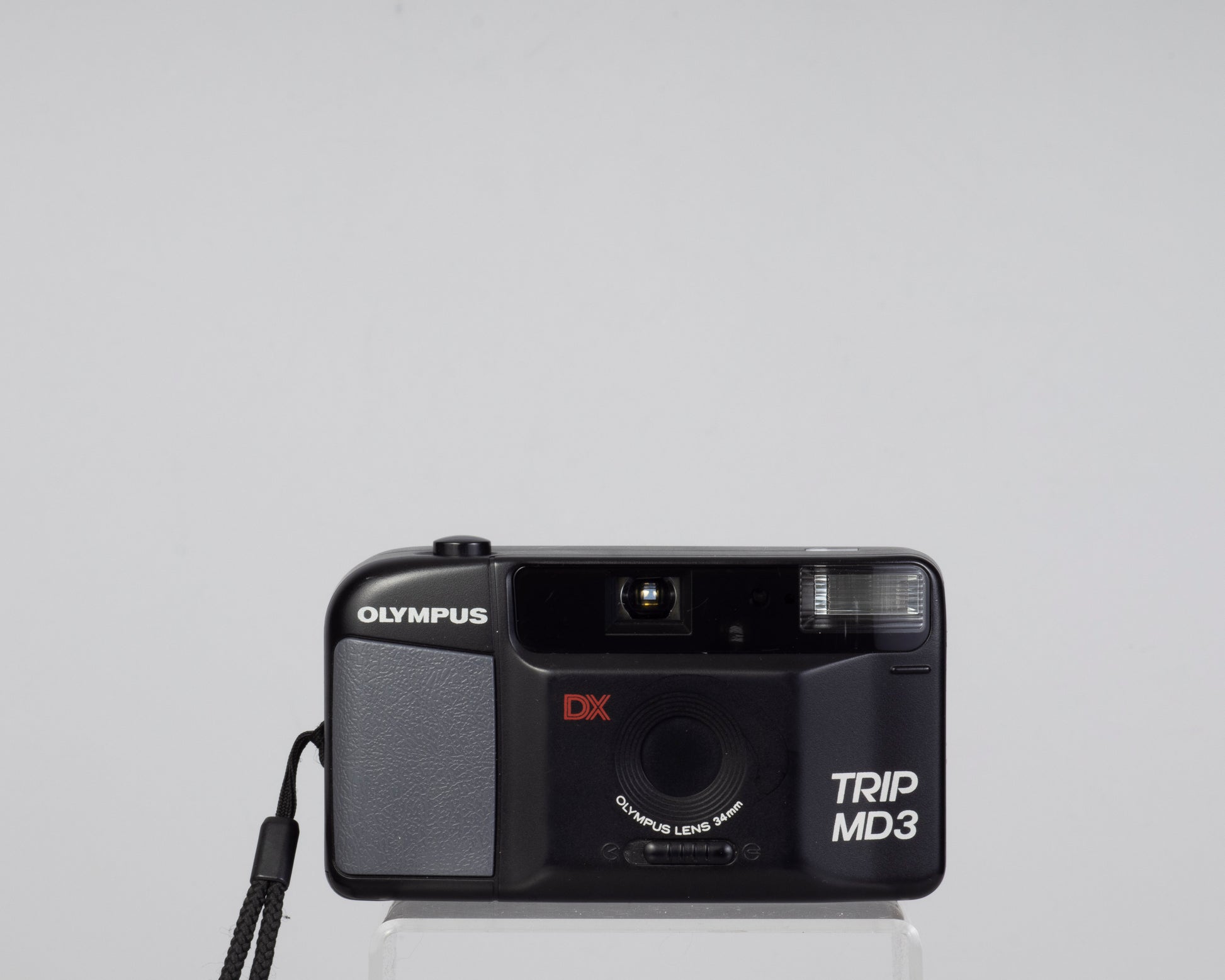 The Olympus Trip MD3 is a simple compact 35mm film camera featuring a fixed 34mm lens